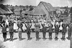 c1905 School children drilling in the school yard. Thatched Village Farm Barn / Langstone House in the background.