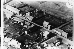 1959. Aerial view of Middle Barton. In the foreground is the cinema with a coach parked beside it.