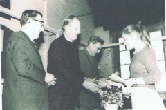 c. 1963/64. Gillian Savage receiving school prize (possibly for poetry) from Rev. Michael Hayter (rector of Steeple Aston school) in Steeple Aston school hall. Others unknown.